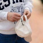 Person holding a cream hat with a blurred background