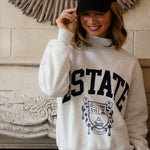 Person wearing a 'ESTATE' sweatshirt and Estate cap in front of a decorative mirror.