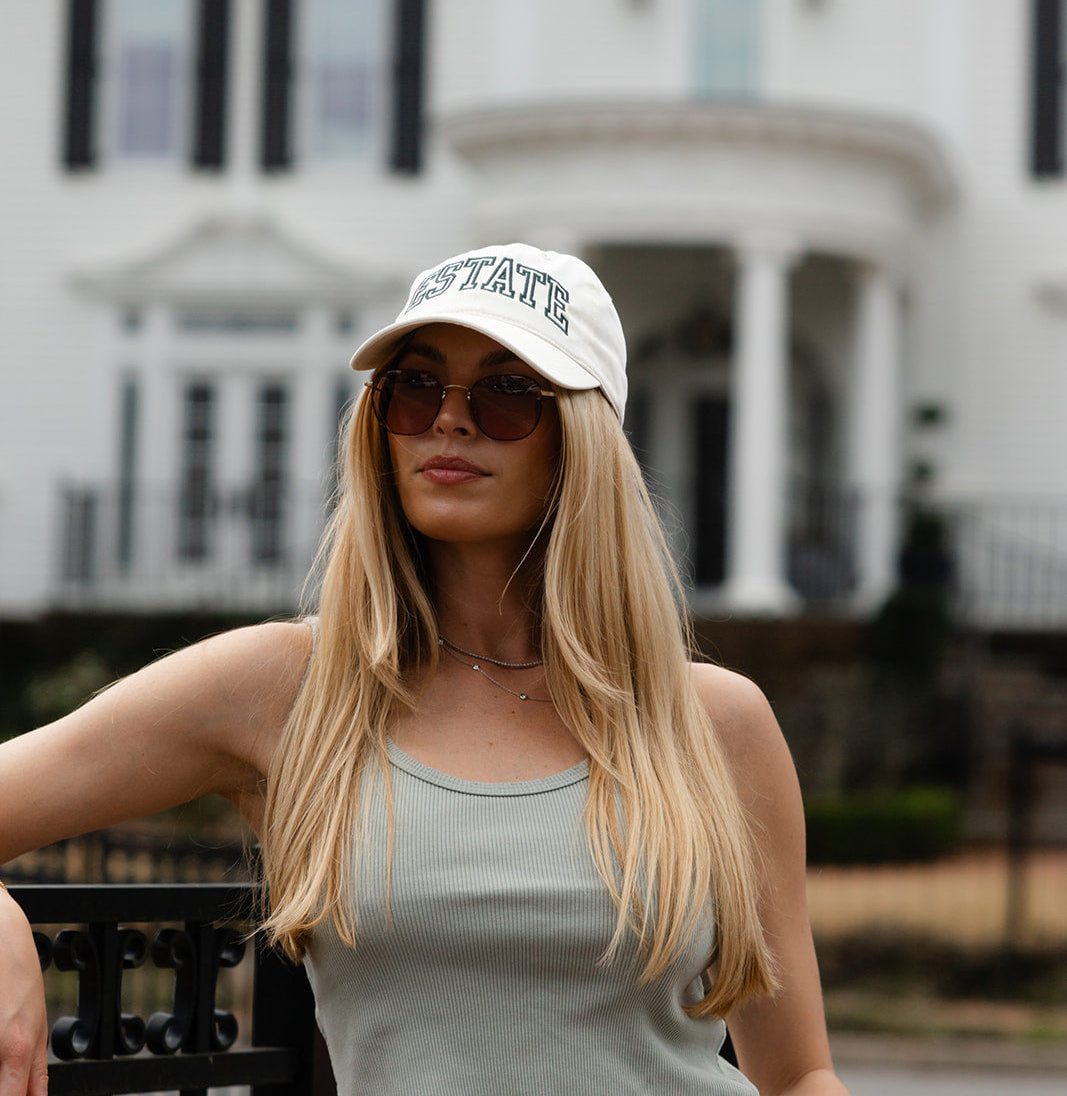 Woman wearing a Thorne Estate hat and sunglasses in front of an estate