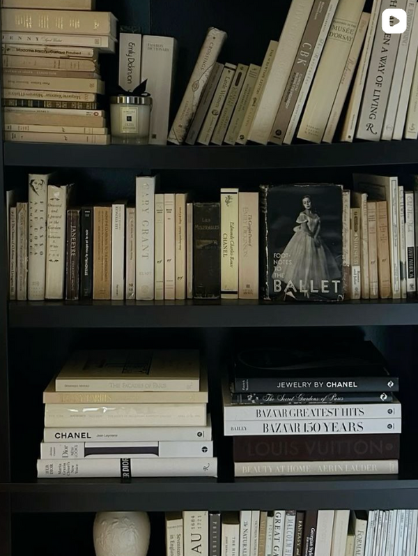 Bookshelf with a variety of books and a candle on a dark background for Thorne Estate's luxury holiday gift guide