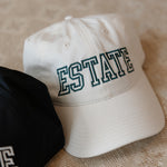 Cream cap with 'ESTATE' text on a textured surface
