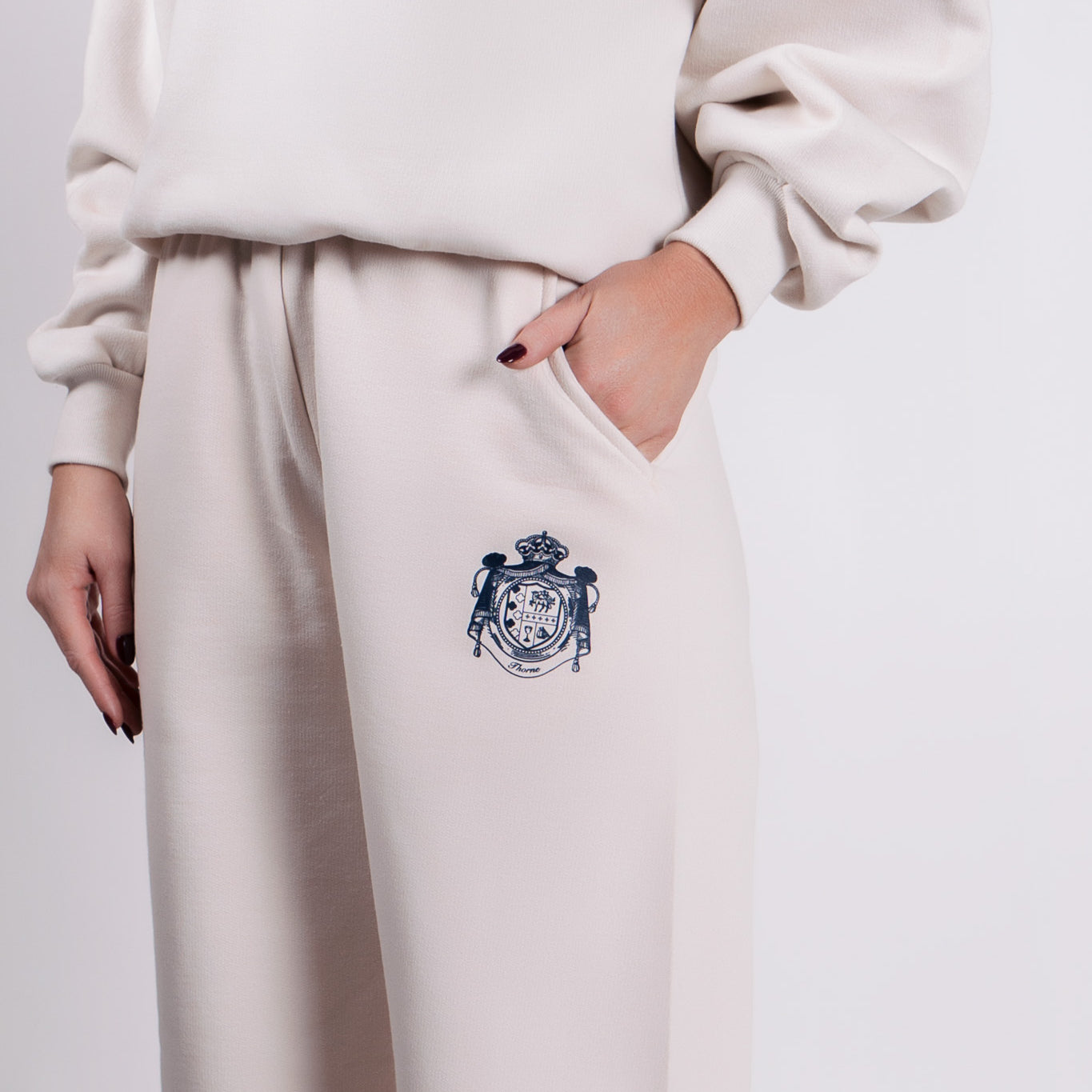 Close-up of Thorne Estate crest embroidery on the cream sweatpant