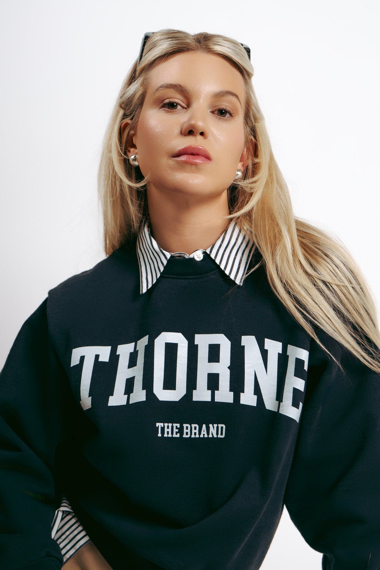Model wearing Thorne Estate varsity collection crewneck styled with a collared button down for a chic look